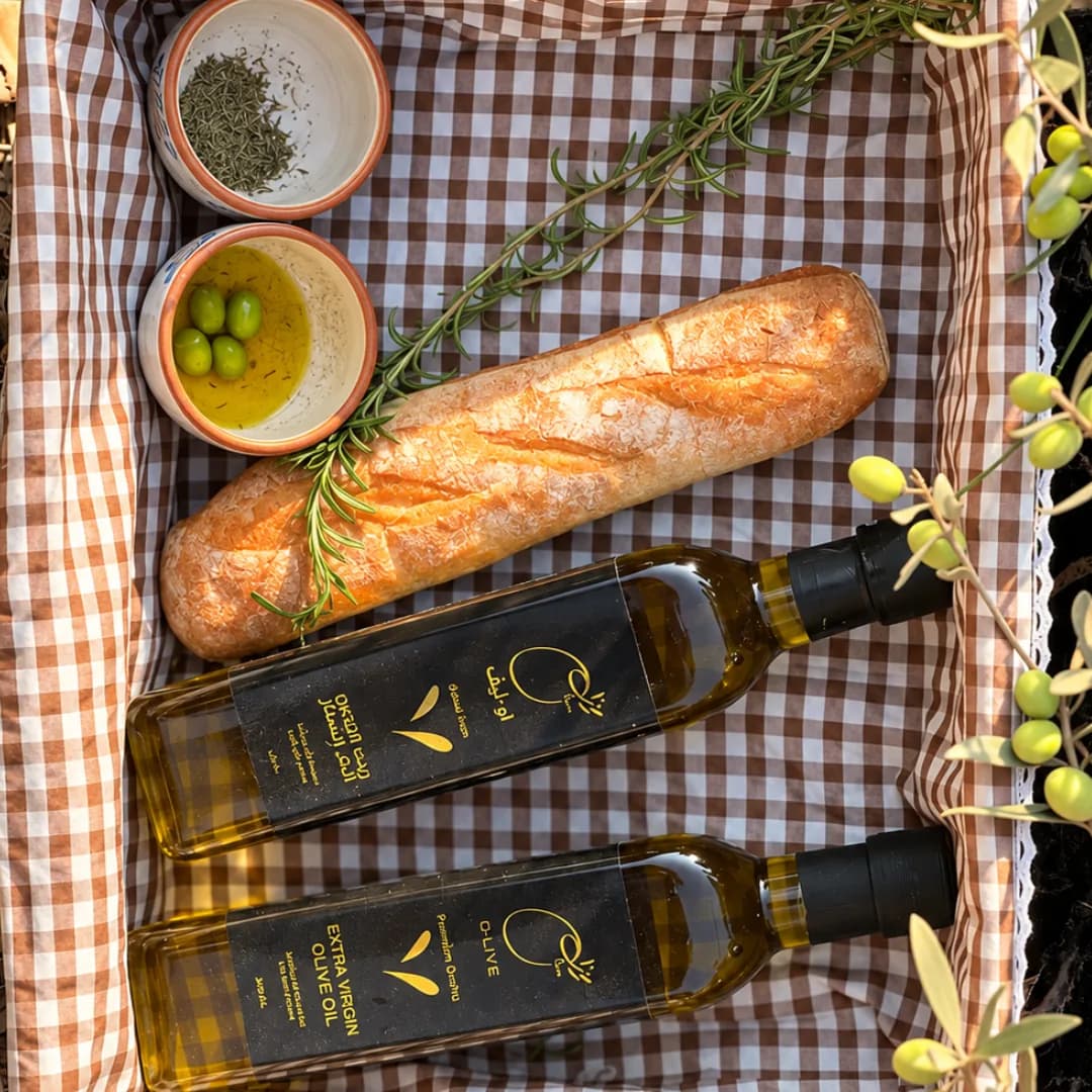 Two O-Live bottles in a picnic basket with bread and olives