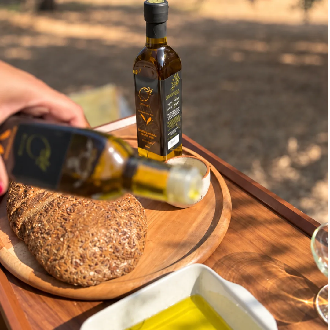 Pouring O-Live oil from the bottle over bread on a wooden board